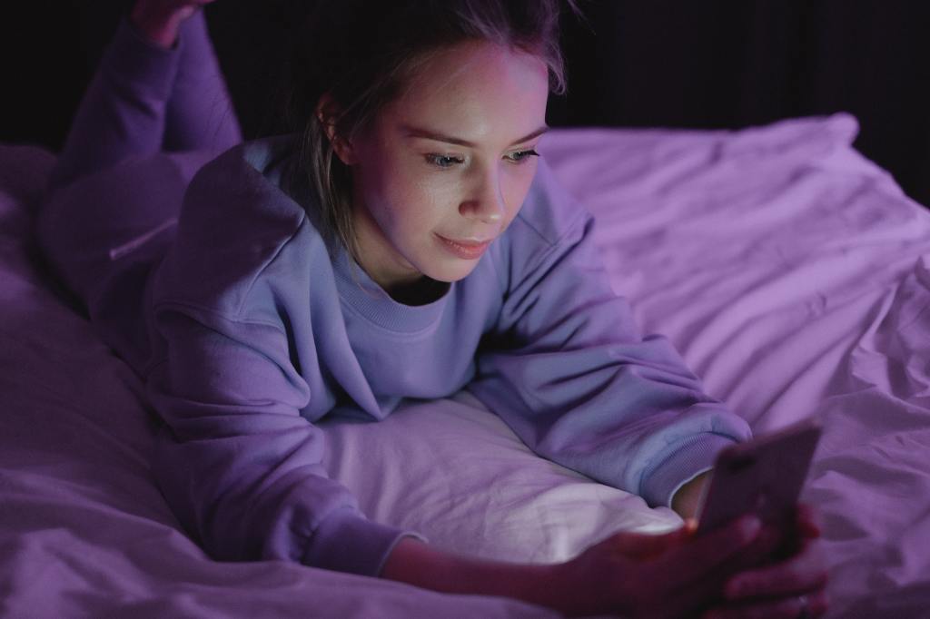 Persona mirando el móvil en la cama